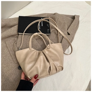 Detail of beige pleated cloud handbag on herringbone coat with sleek strap and soft leather