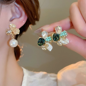 Détail de boucles d'oreilles perle vintage avec strass verts et épingles en argent