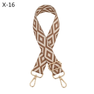 Macro detail of brown and beige geometric rhombus jacquard bag strap with gold metal hooks