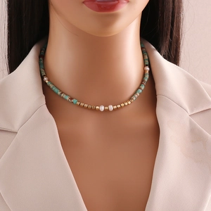 Handmade necklace with natural turquoise beads, white pearls, and gold accents on a model