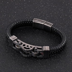 Detail of black woven leather bracelet with antique silver gear charm and magnetic clasp