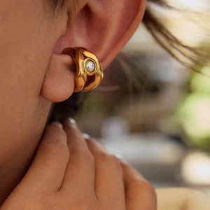 Elegante earcuff in acciaio dorato con perla centrale indossato da una modella