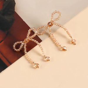 Detail of champagne crystal bead bow earrings with diamond-shaped dangling drops