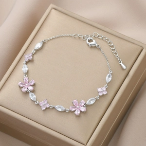 Macro shot of silver-tone floral bracelet with pink zircon petals on champagne silk