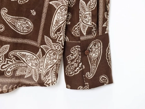 Detail of paisley print long sleeve shirt cuff and hem with brown button texture