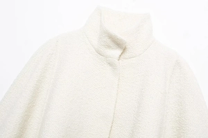 Close-up of elegant white tweed stand collar jacket with high-quality fabric texture