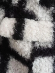 Macro shot of black and white checkered faux fur fabric texture for cocoon winter coat