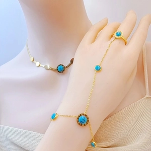 Detail of gold finger bracelet and disc necklace set with green turquoise stones