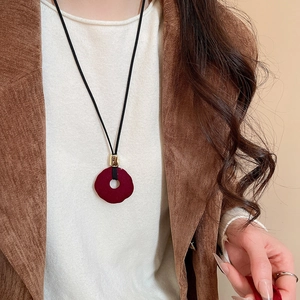 Detail of a vintage red flocked resin pendant on a black cord necklace with golden clasp