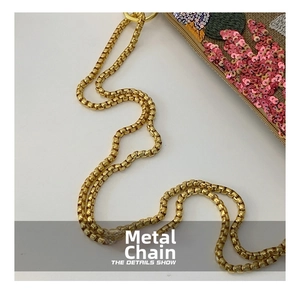 Close-up of golden box chain and intricate floral sequin embroidery on messenger bag