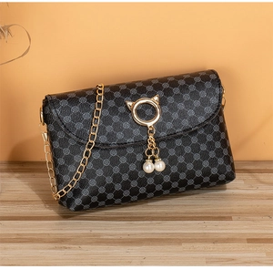 Detail of black quilted chain bag with gold cat-ear ring clasp and pearl pendants