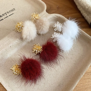 Detail of plush pompom earrings with sparkling zircon snowflake charms in various colors
