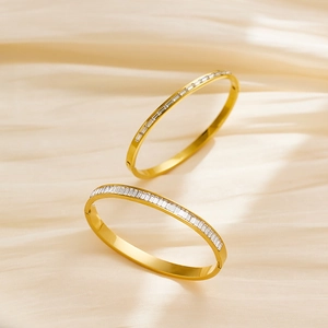Close-up of two gold titanium steel bangles with pave diamonds on champagne silk