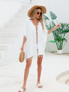Détail de la robe de plage boho blanche avec textures crochetées et pompons frangés