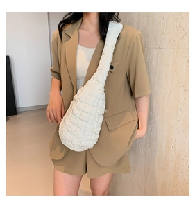 Détail d'un sac bandoulière blanc en tissu matelassé porté par un mannequin de mode