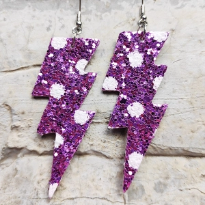 Dettaglio di orecchini a forma di fulmine glitterati viola con motivi a pois bianchi
