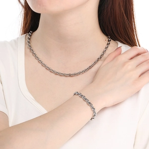 Close-up of polished stainless steel link necklace and bracelet worn by a model