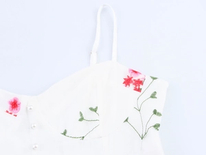 Détail de broderie florale et de boutons de perles sur la robe en tulle blanc