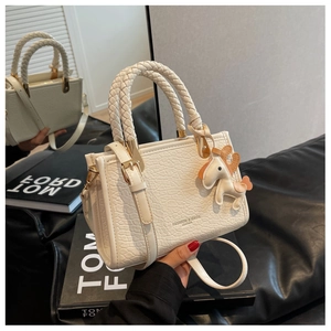 Detail of off-white crocodile embossed bucket bag with woven handle and gold hardware