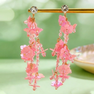 Close-up of long pink floral tassel earrings with frosted flower and bead details