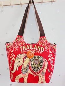 Detail der roten Canvas-Tasche mit Elefanten-Stickerei, Thailand-Schriftzug und Holzknopf