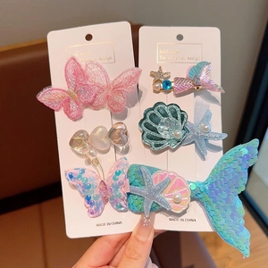 Détail de barrettes océan avec queue de sirène à paillettes et papillon brodé