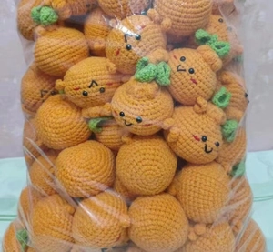 Bulk hand-crocheted orange fruit pendants with green leaves stored in clear packaging