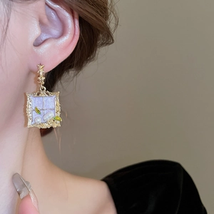 Vintage gold rectangle earrings with pearls and green enamel leaf detail worn by a model