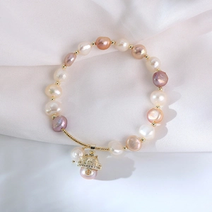 Macro shot of colorful freshwater pearls and gold lucky cat pendant on silk background