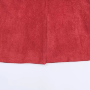 Detailed close-up of red suede fabric texture with stitching seam and hemline finish