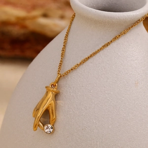 Detail of 18K gold plated stainless steel hand pendant holding a clear sparkling diamond