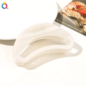 Detail shot of a large cream translucent arched hair claw clip on a minimalist white surface