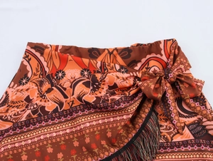 Detail of bohemian mini skirt showing waist tie knot and black tassel fringe trim