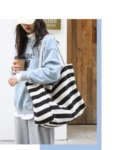 Lifestyle view of a black and white striped canvas tote bag with a casual street style