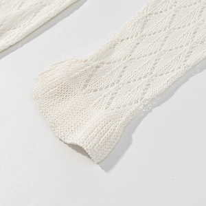 Detailed macro shot of white crochet knit sleeve showing diamond镂空 pattern and elastic cuff