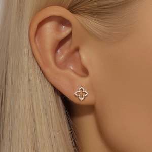 Close-up of gold-plated hollow four-leaf flower earrings with micro-pave zircons on ear