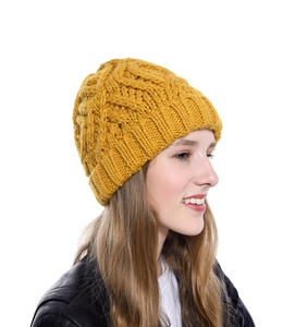 Detail showing the thick diamond pattern knit texture of a yellow winter beanie for women