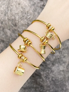 Detalle de cuatro pulseras chapadas en oro de 18k con colgantes de café en la muñeca