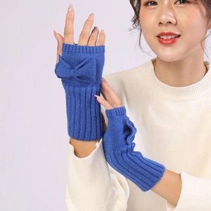 Detail view of royal blue knitted fingerless gloves with bow decoration on a model