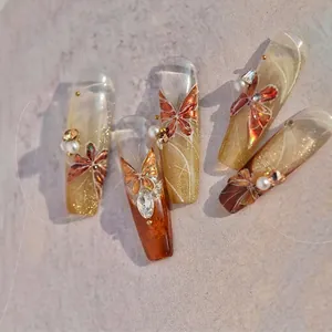 Detailed view of amber butterfly nail stickers with rhinestones and golden glitter accents