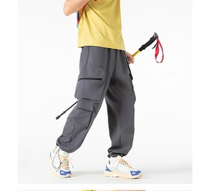 Dettaglio dei pantaloni cargo grigio scuro con tasche con zip e polsini affusolati