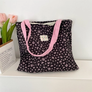 Detail of floral bubble crepe fabric and pink straps on a black shoulder bag