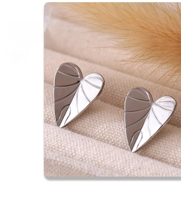 Macro detail of silver leaf-vein textured heart earrings on a soft jewelry box