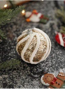 Detail der goldenen Pailletten-Weihnachtskugel mit weißem Plüschstreifen auf Schnee