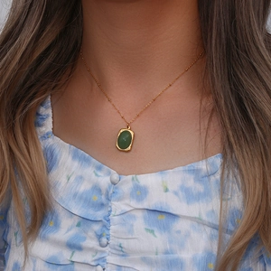 Detailed shot of a vintage gold necklace featuring a green oval natural stone pendant