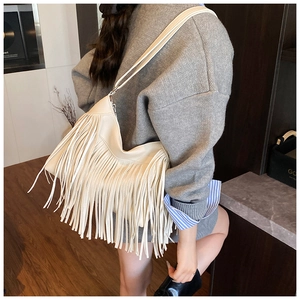 Model view of cream tassel crossbody bag showing large capacity in indoor setting