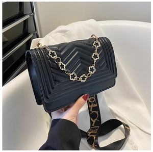 Detail of black quilted shoulder bag with V-shaped stitching and golden plum chain strap