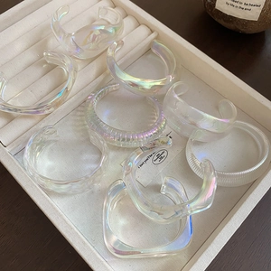 Detailed view of iridescent white acrylic geometric bangle set on a jewelry tray