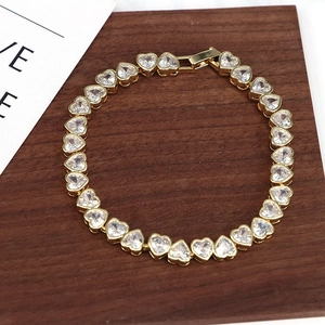 Close-up of golden heart-shaped zircon bracelet with secure clasp on wooden background