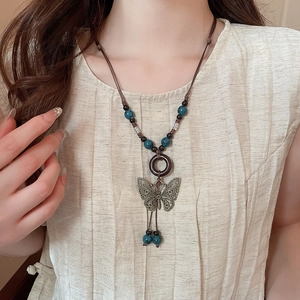 Detailed shot of bronze butterfly pendant with turquoise beads on ethnic necklace